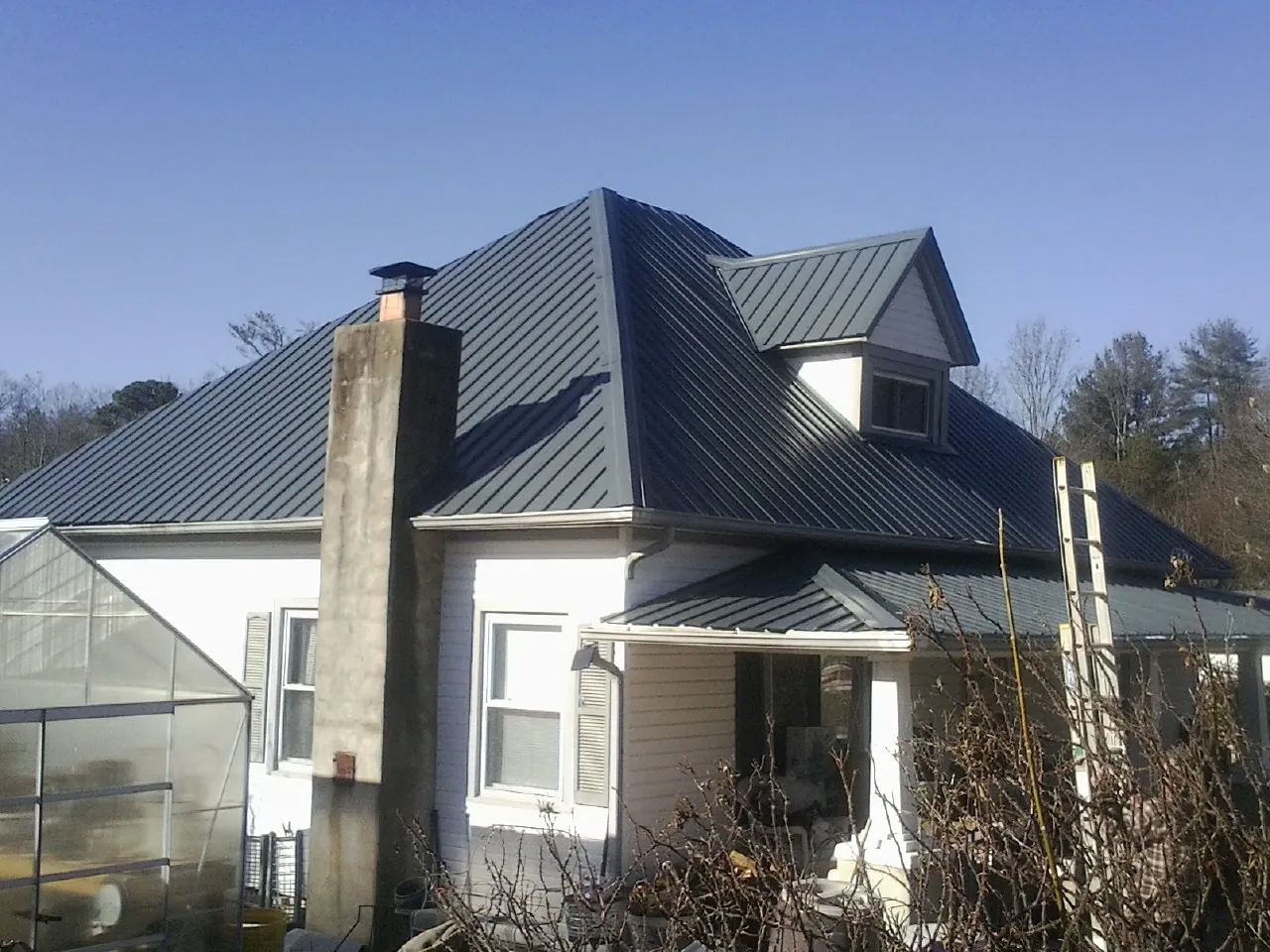 Dark blue standing seam metal roof on a white farmhouse with dormer — Slate & Tile Roof Repair by Roofing Brothers in Shawmut