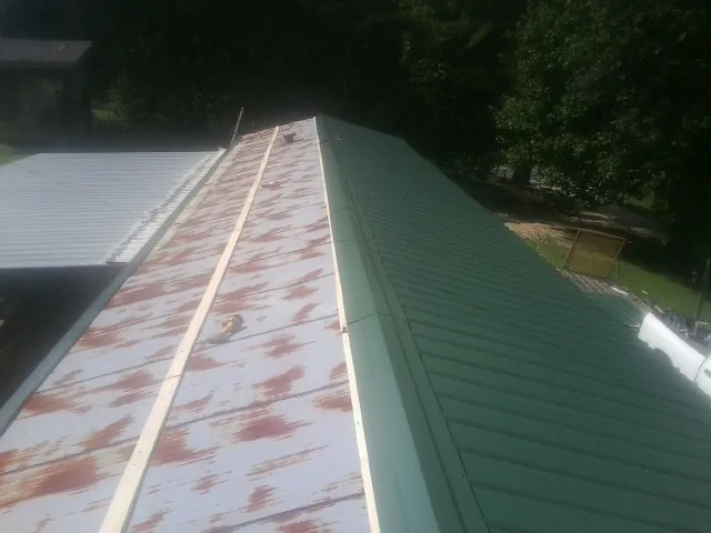 Old rusted panels beside newly installed green metal roofing — Wind Damage Roof Repair by Roofing Brothers in Shawmut