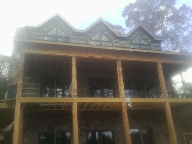 Dormers and porch framing on a large log home under construction — Roof Coating work by our crew in Shawmut