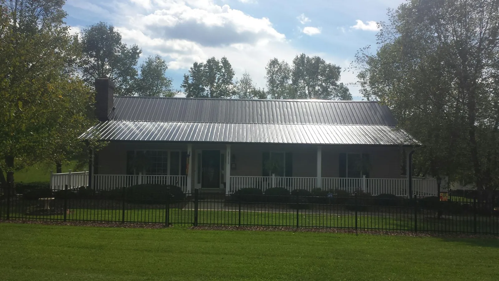 Gray metal roof on a brick ranch with a full width front porch — Gutter Guard Installation work by our crew in Shawmut